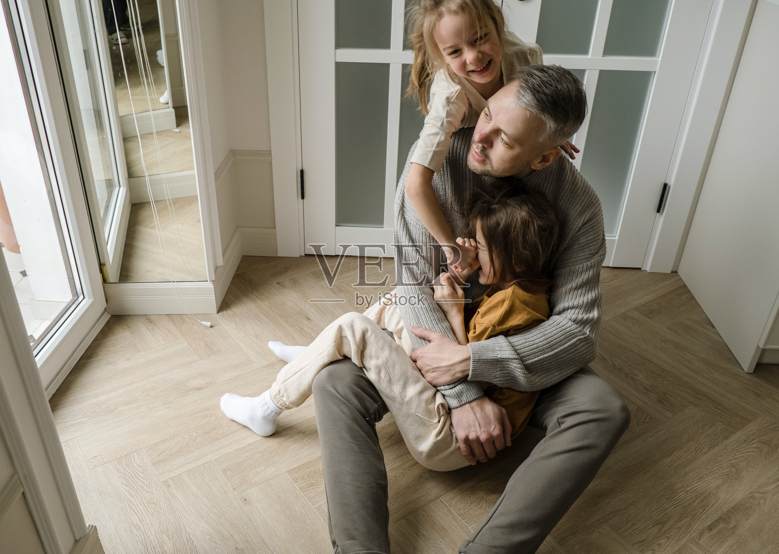 一位父亲被两个女儿的爱与欢笑所包围。照片摄影图片