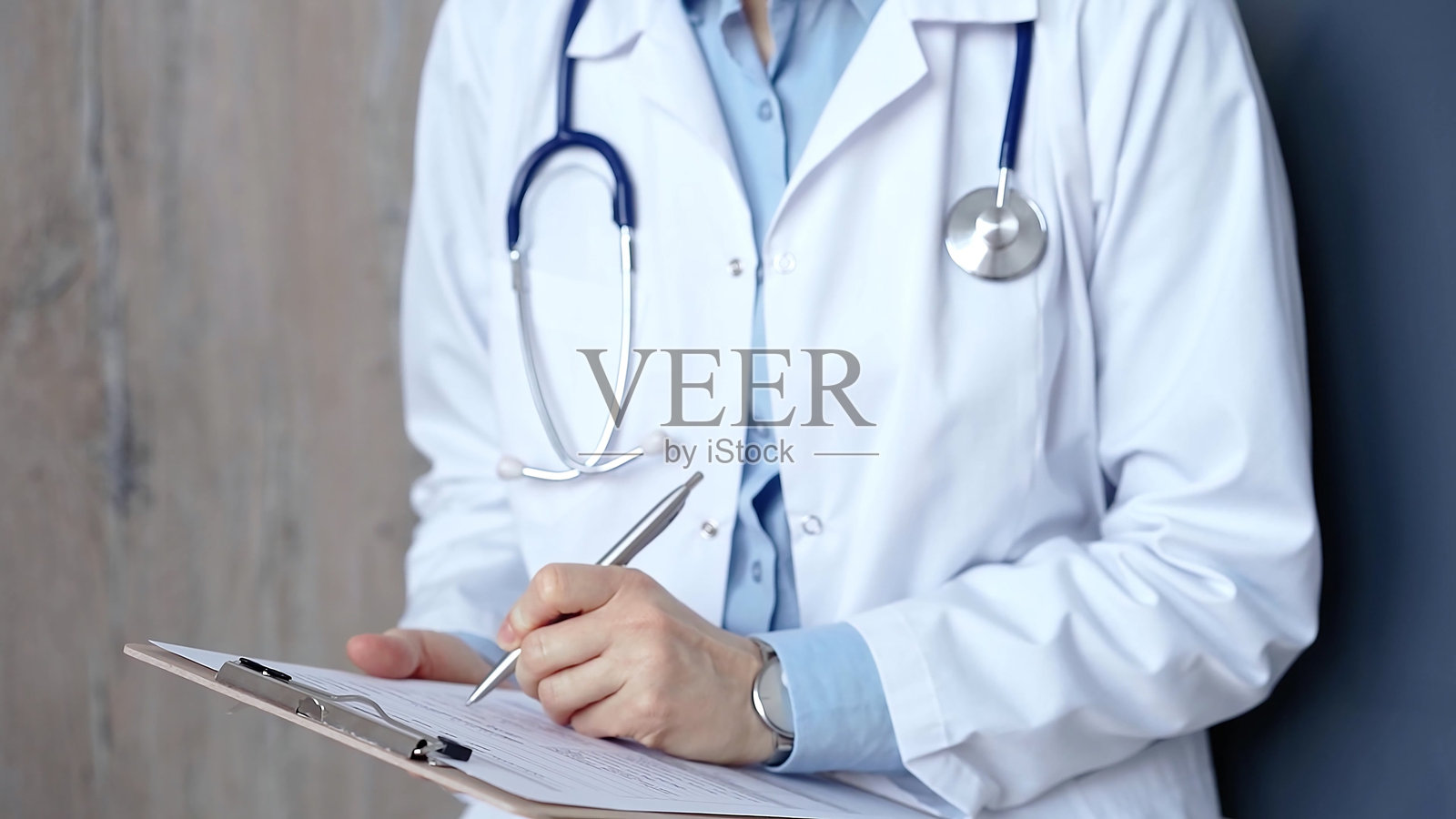 医疗专业人员医生在夹板上记录病历。女性不可识别的医生在工作。医学与药学照片摄影图片