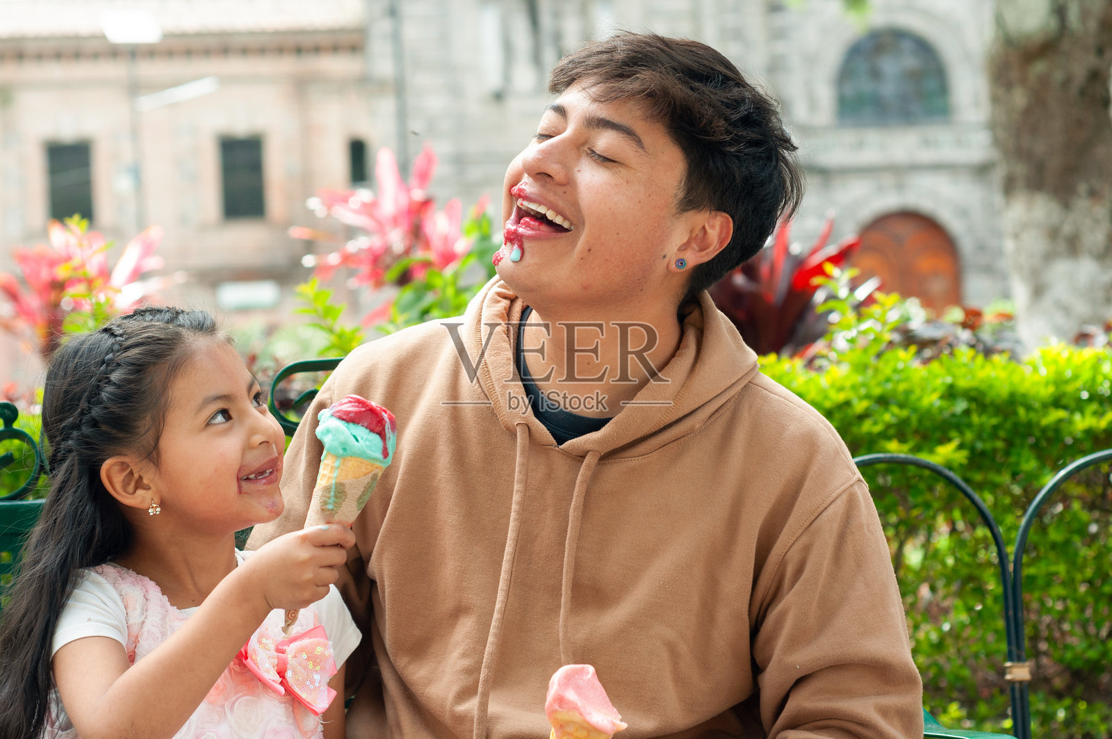 父女俩在一个有趣、顽皮的时刻中，因冰淇淋弄得一团糟而哈哈大笑。照片摄影图片
