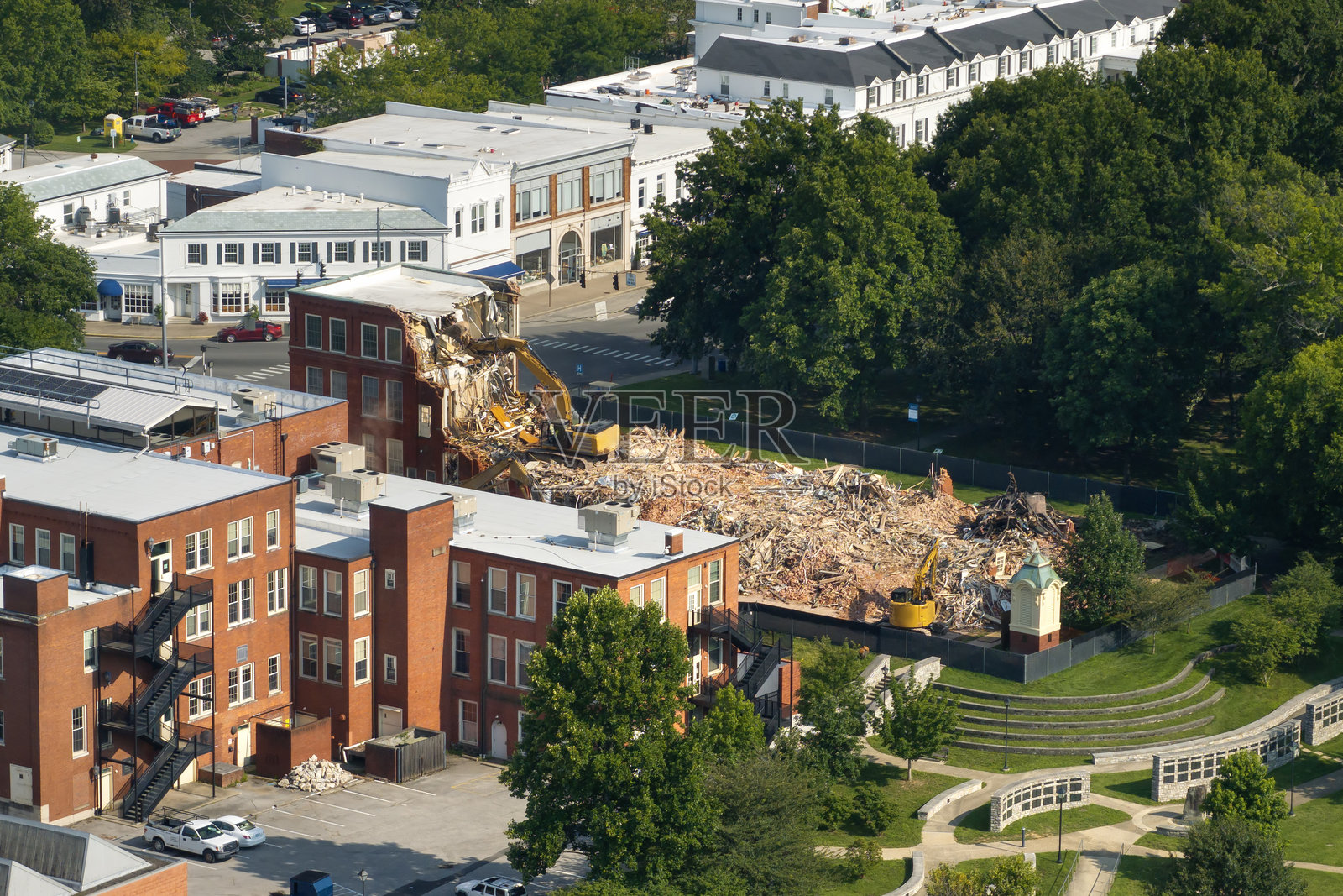 拆除旧住宅楼。履带式挖掘机正在拆除过时建筑的砖墙。照片摄影图片