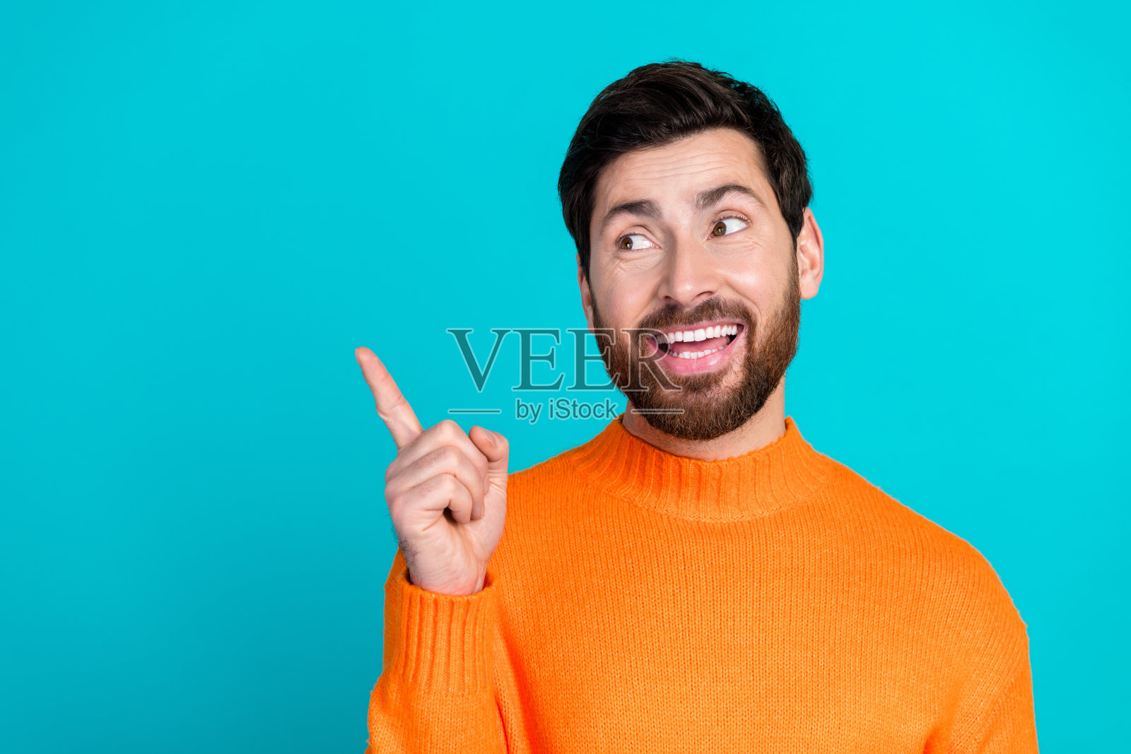 穿着橙色时尚服装的迷人帅气男士在青色背景前展示空白空间照片摄影图片