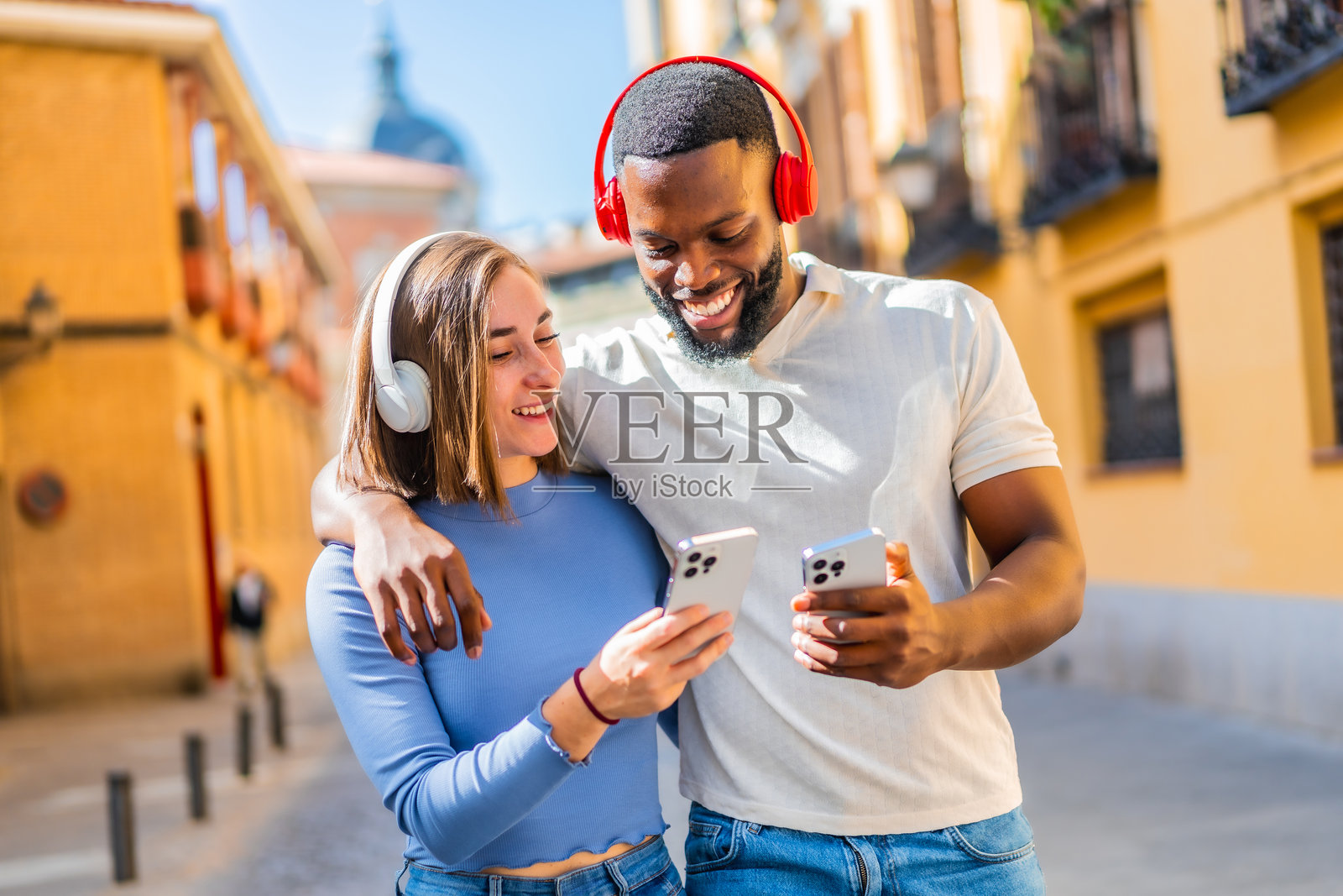 快乐的多民族情侣在城市中使用手机听音乐照片摄影图片