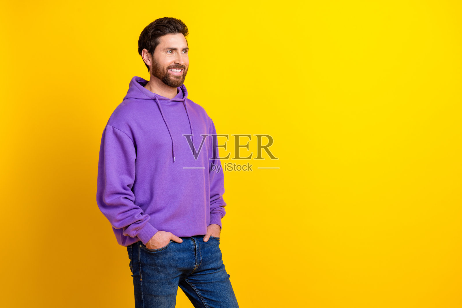 年轻男性的照片肖像，穿着时尚的紫色服装，面向空旷的空间，背景为黄色。照片摄影图片