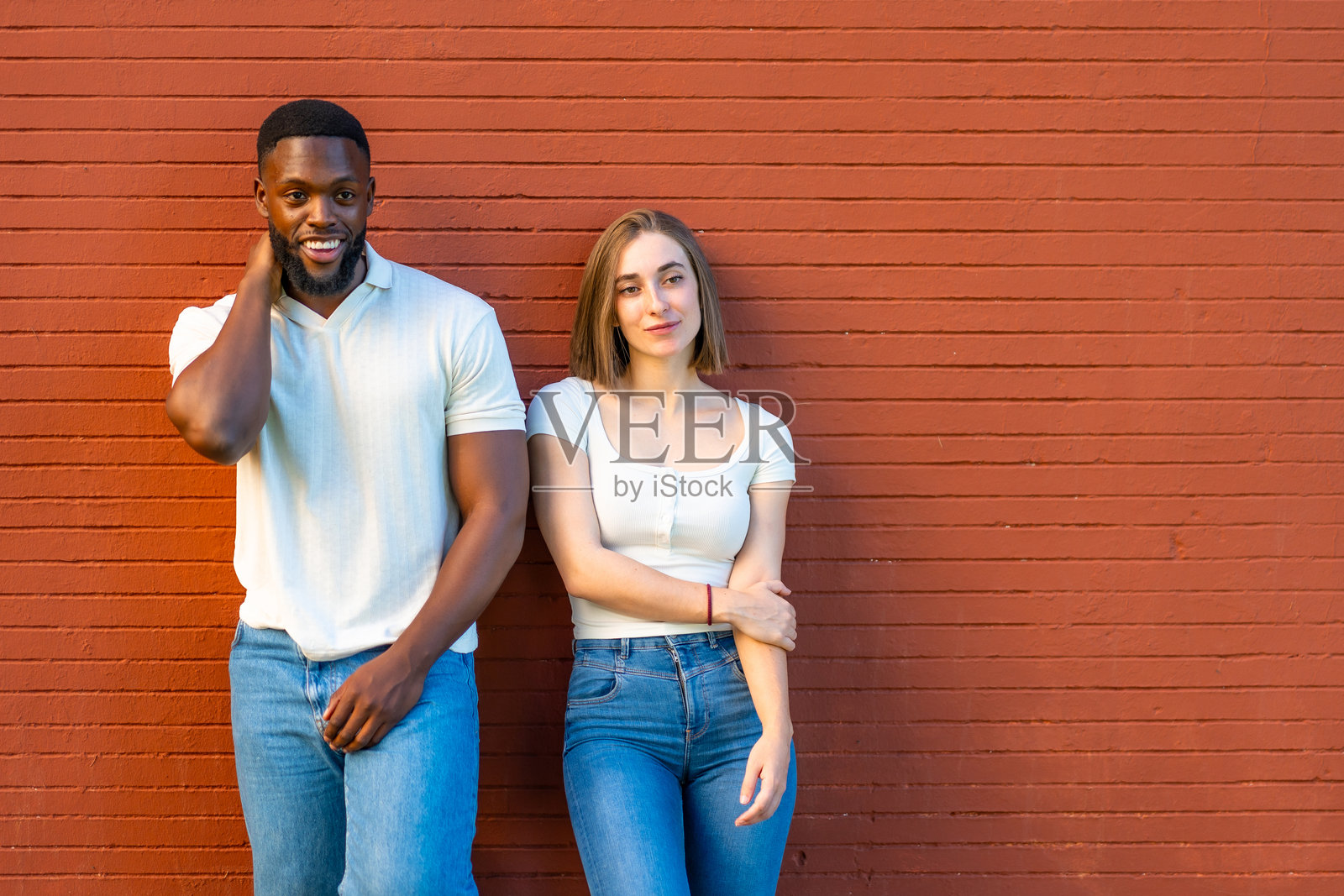 害羞的多民族情侣依偎在城市墙壁上照片摄影图片