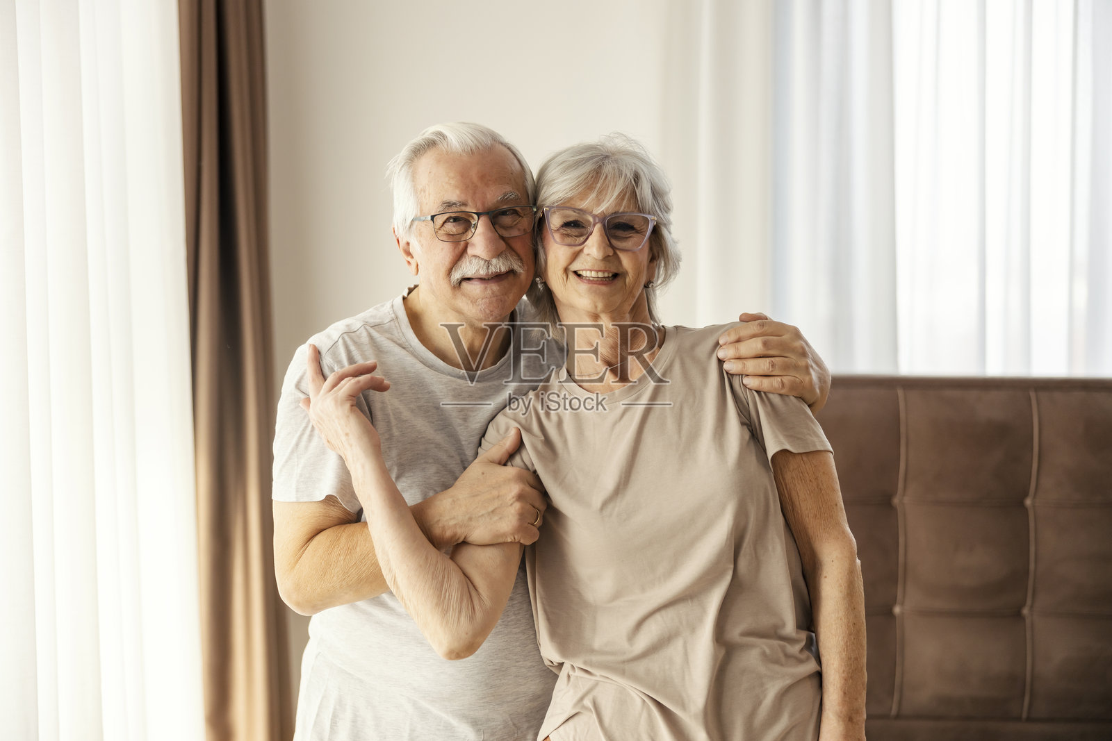 一对亲密的老年夫妇在养老院的卧室里相拥而立。照片摄影图片