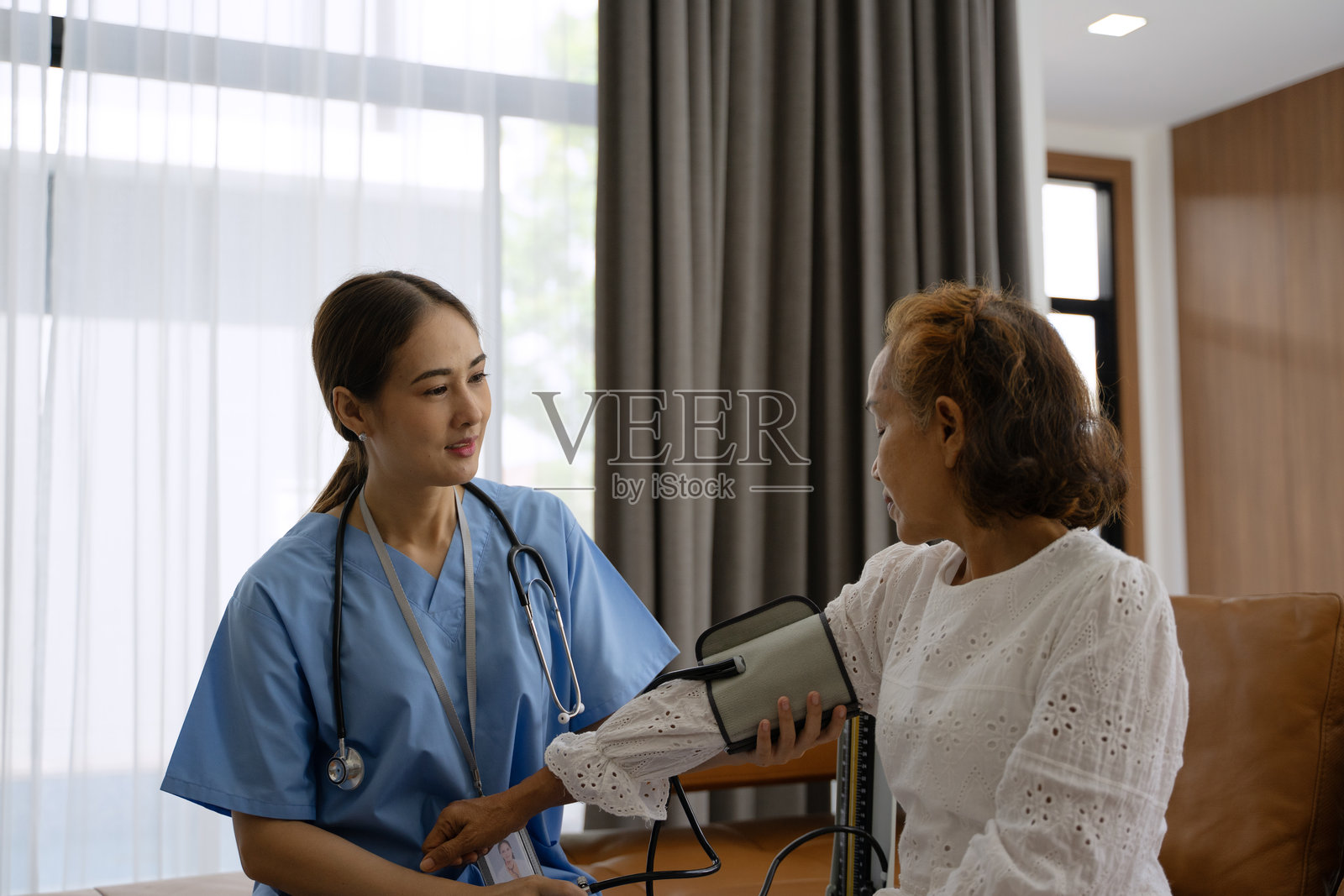 护士在家中照顾一位年长女性，使用听诊器。照片摄影图片