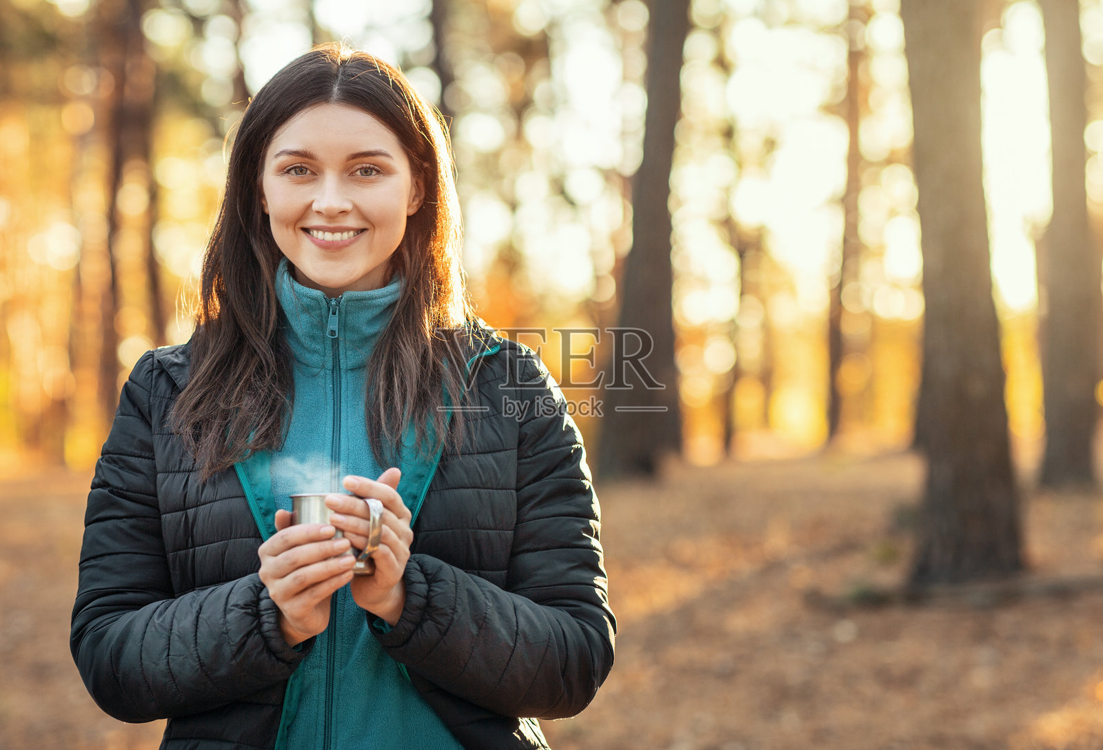 快乐的女孩在森林里捧着茶杯取暖照片摄影图片