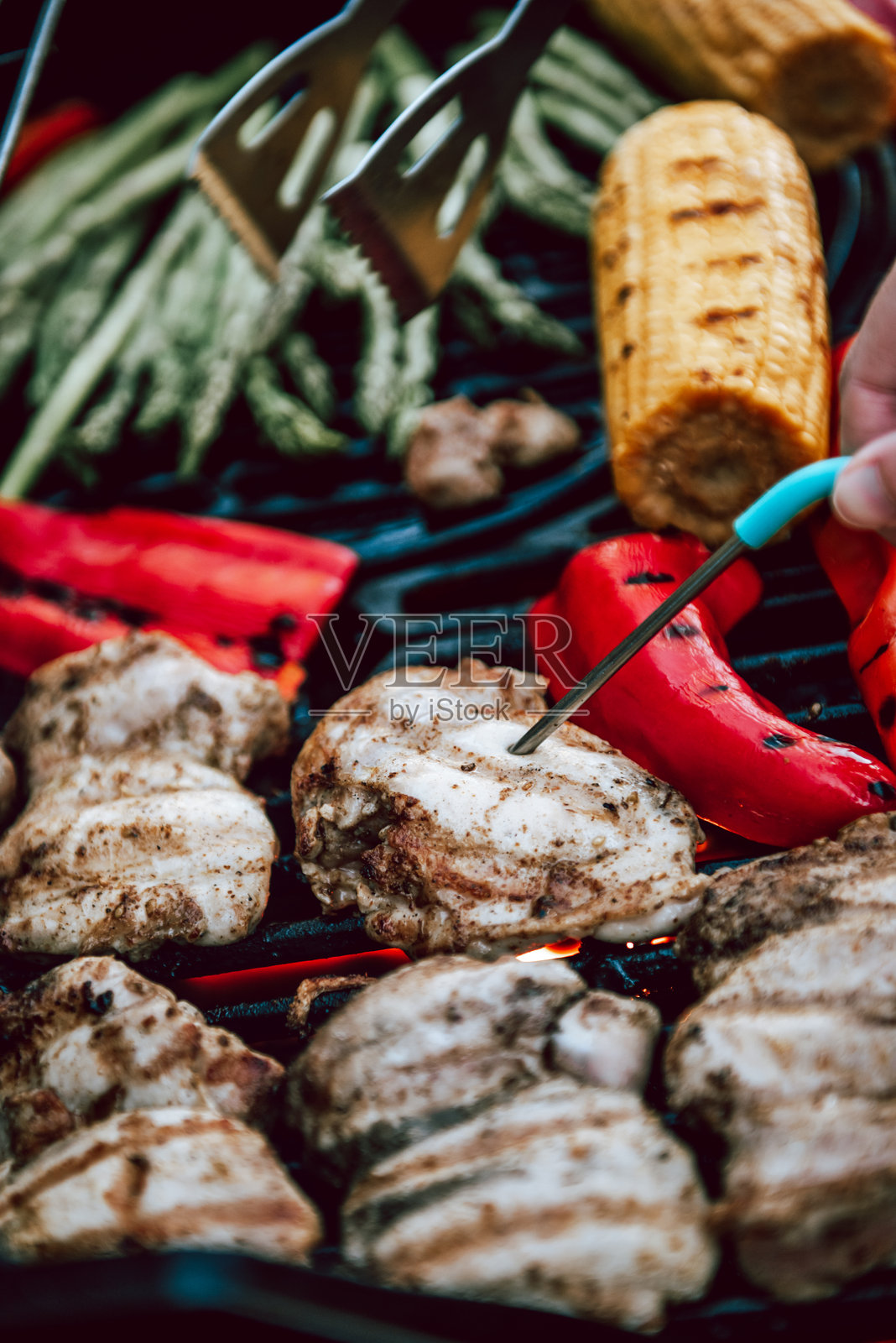 烟雾缭绕的烧烤架上，烤鸡肉与蔬菜同烹。照片摄影图片