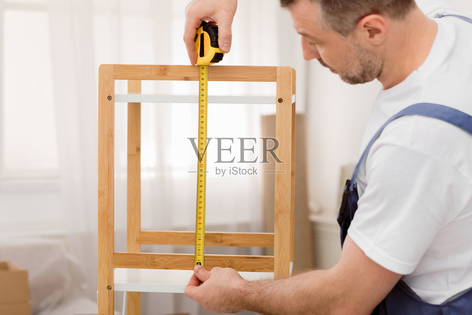 专业木匠在室内用卷尺测量架子照片摄影图片