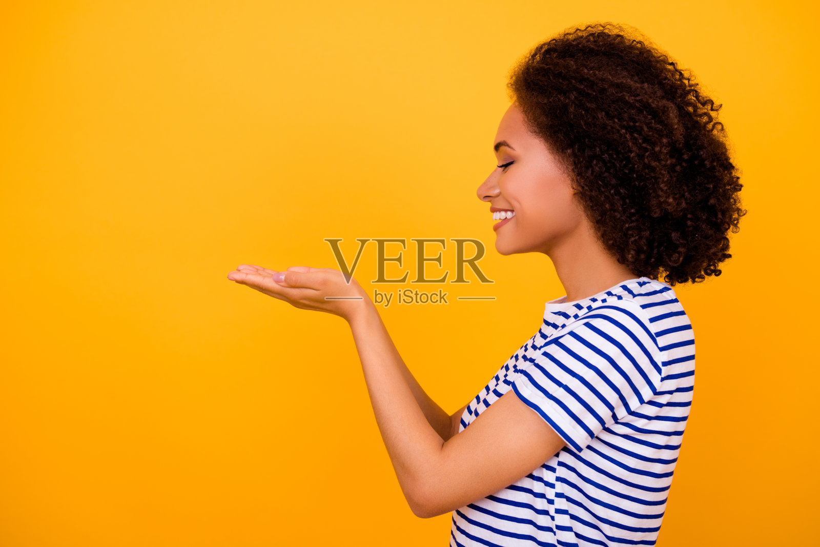 漂亮开朗的人用手掌展示空白空间，背景为黄色。照片摄影图片