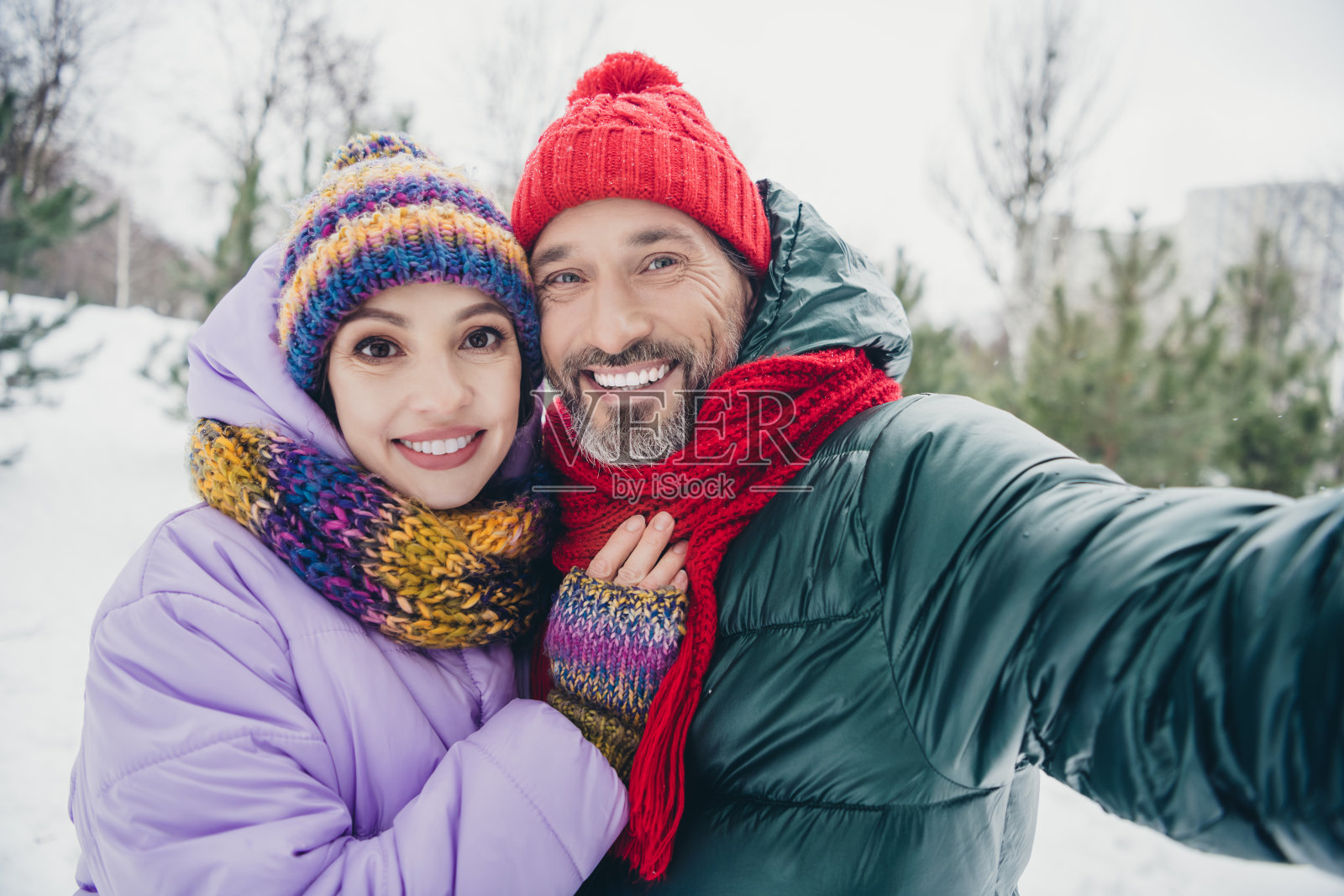 穿着外套的积极兴奋的妻子和丈夫在城市森林公园户外拥抱录制视频博客照片摄影图片