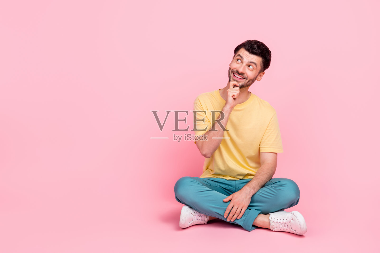 穿着时尚黄色衣服的聪明机智男子，目光专注地看向空旷的空间，背景为粉色。照片摄影图片