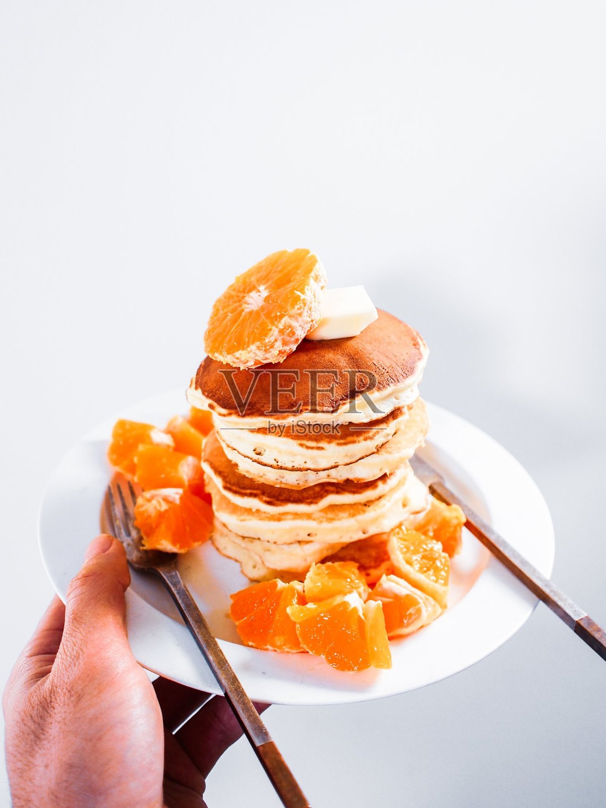 健康的夏季早餐，自制经典美式煎饼配新鲜浆果和蜂蜜，晨光下的灰色石材背景，顶部留白。照片摄影图片