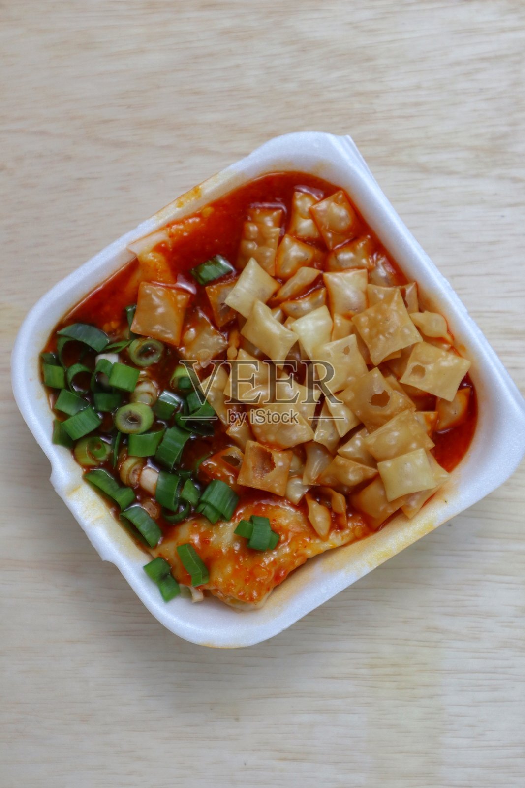 辣味馄饨，上面放有饺子块和葱花照片摄影图片