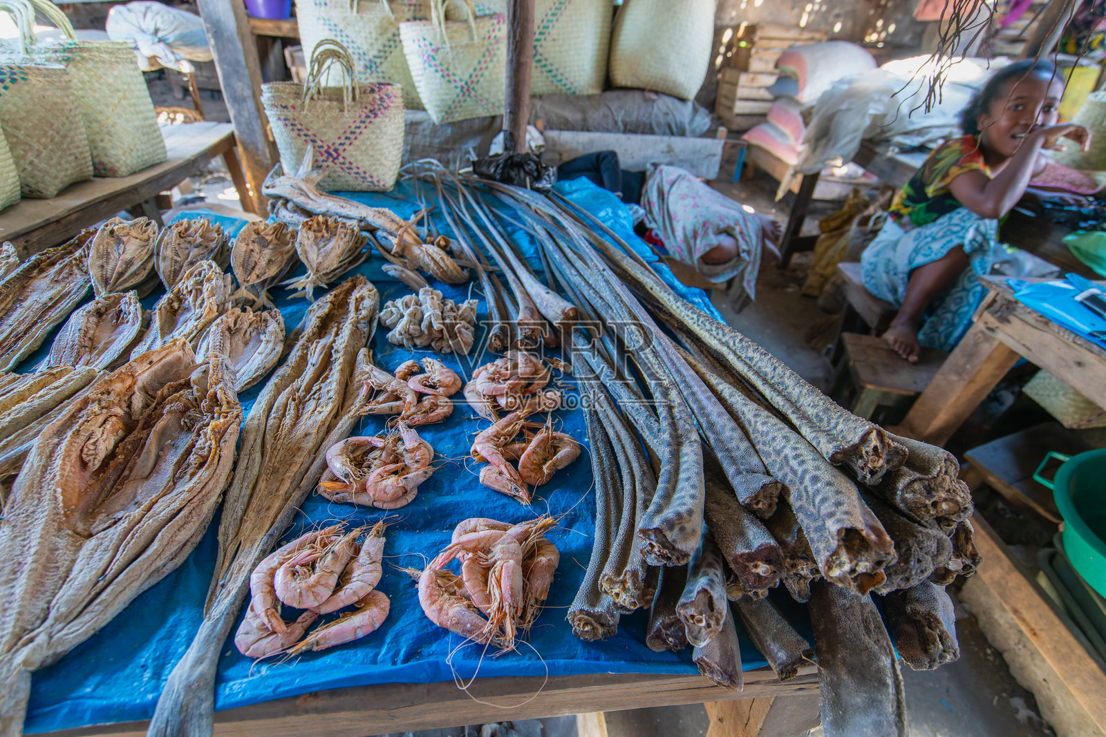 一个年轻女孩在莫隆达瓦市场照看一个干海鲜摊位。照片摄影图片