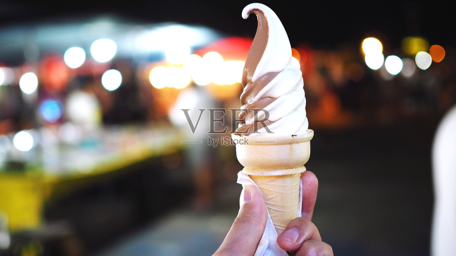 夜晚手握冰淇淋蛋筒照片摄影图片
