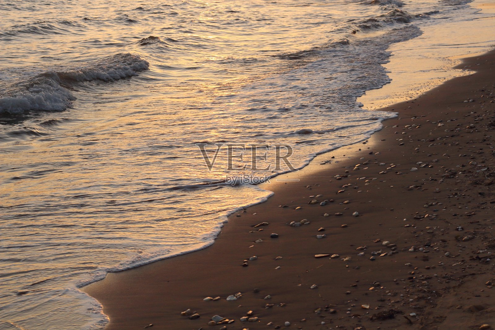 日落为海洋和沙滩洒下温暖的金色光辉照片摄影图片