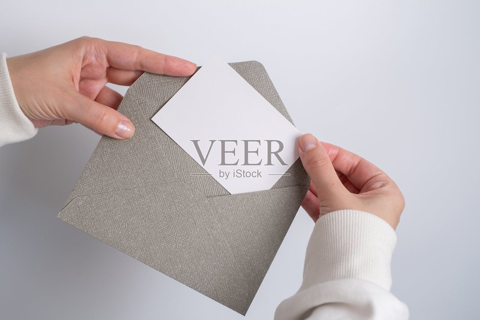 年轻女孩手中拿着纸质信封。新邮件，信息。邮政服务。她想发送或接收信件。空白信封，空白空间。人际沟通概念。信封模型特写。照片摄影图片