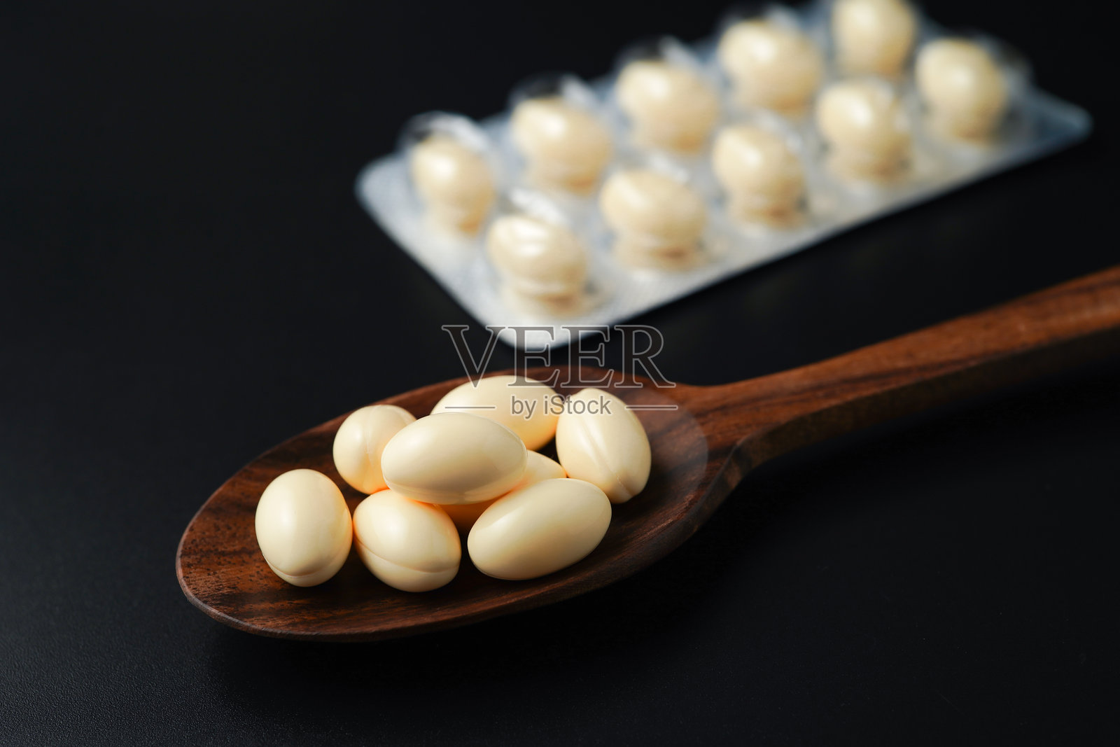 木勺中的白色软胶囊，含有维生素E、鳕鱼肝油、DHA和鱼油Omega-3照片摄影图片