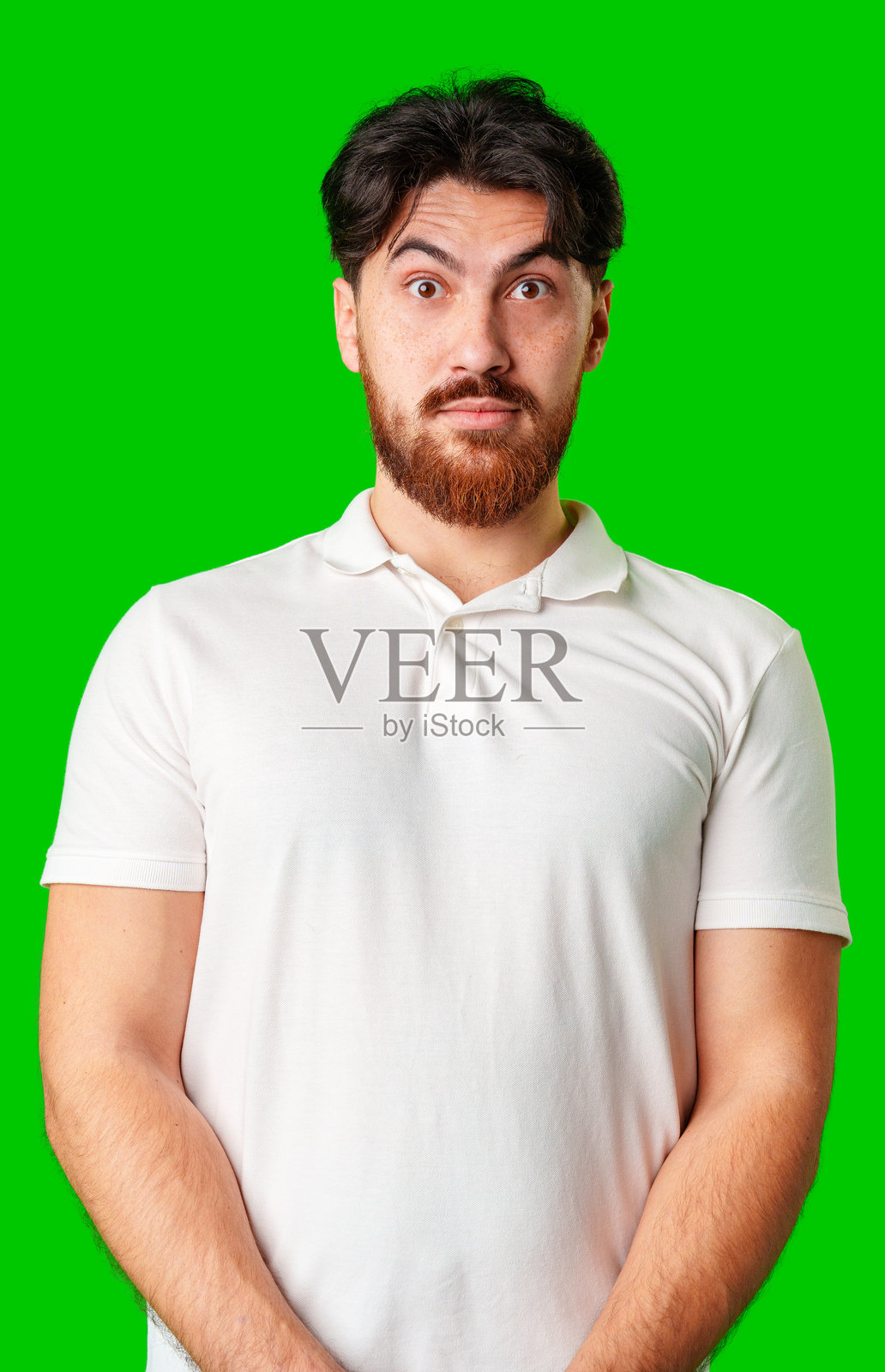 一名面露严肃表情的男子站在生机勃勃的绿色背景前照片摄影图片