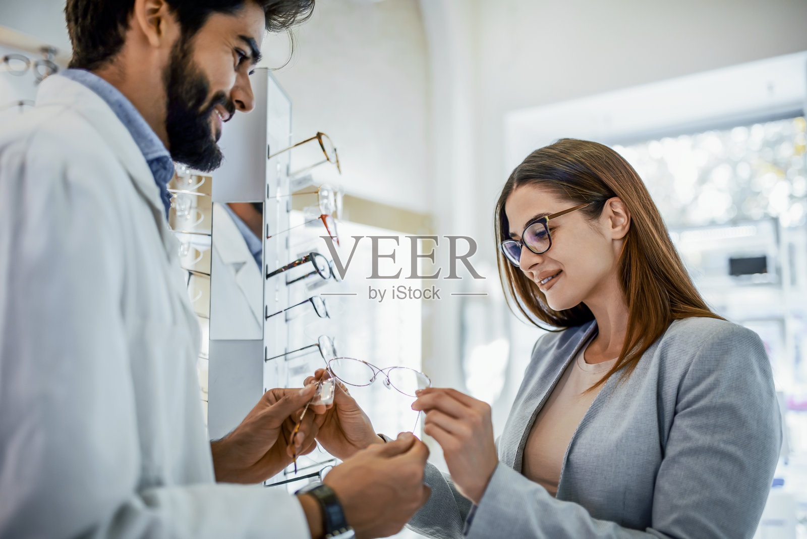 年轻女性在眼镜店挑选新眼镜。医疗，健康护理概念照片摄影图片