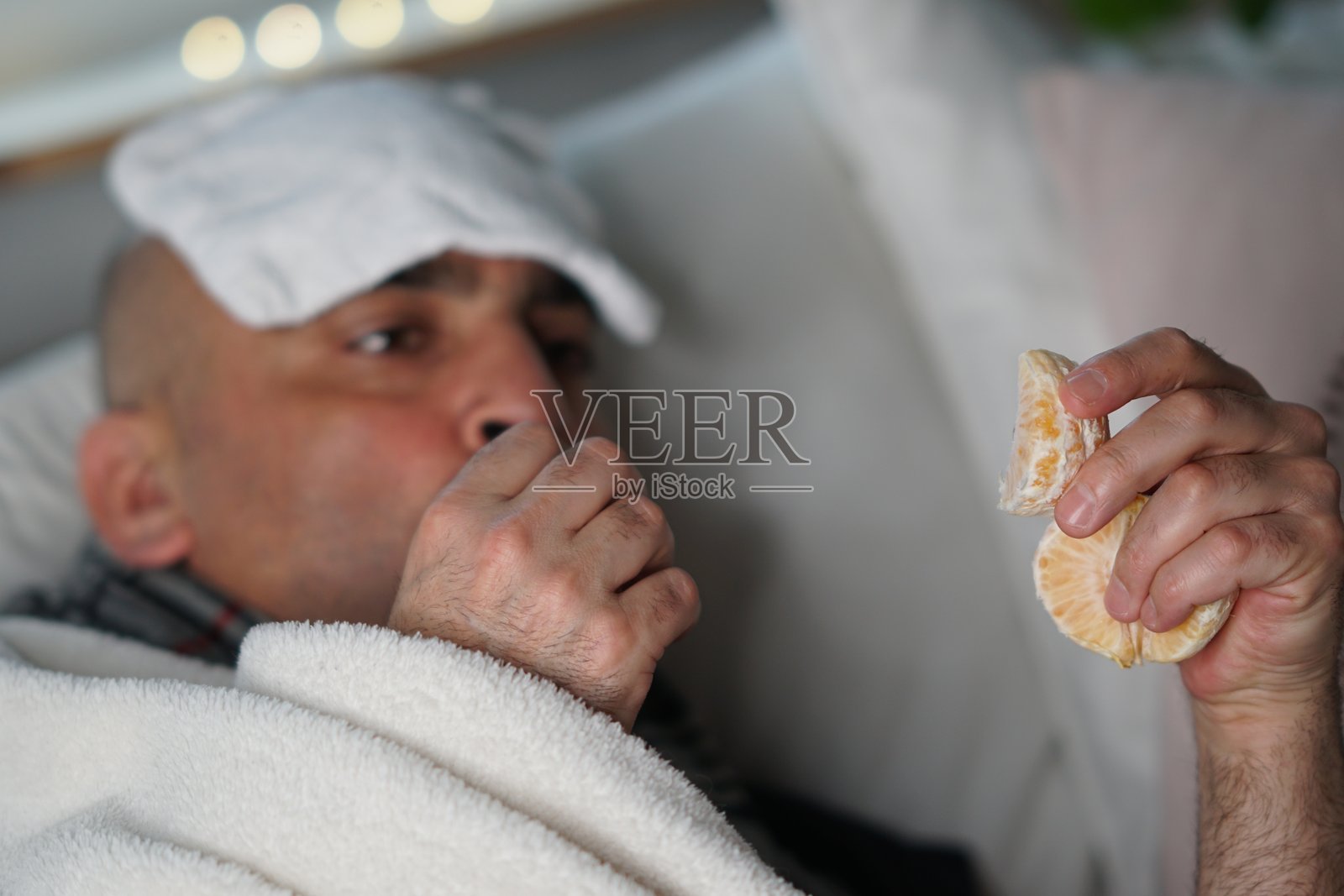 躺在沙发上的男人特写，正吃着橙子照片摄影图片