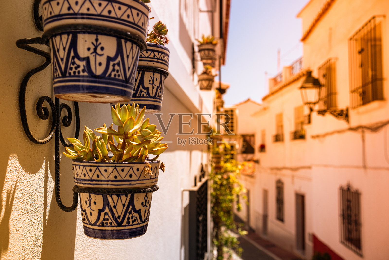 墙上固定着花卉的图案陶瓷花瓶，装饰着西班牙内尔哈古镇的老房子。照片摄影图片