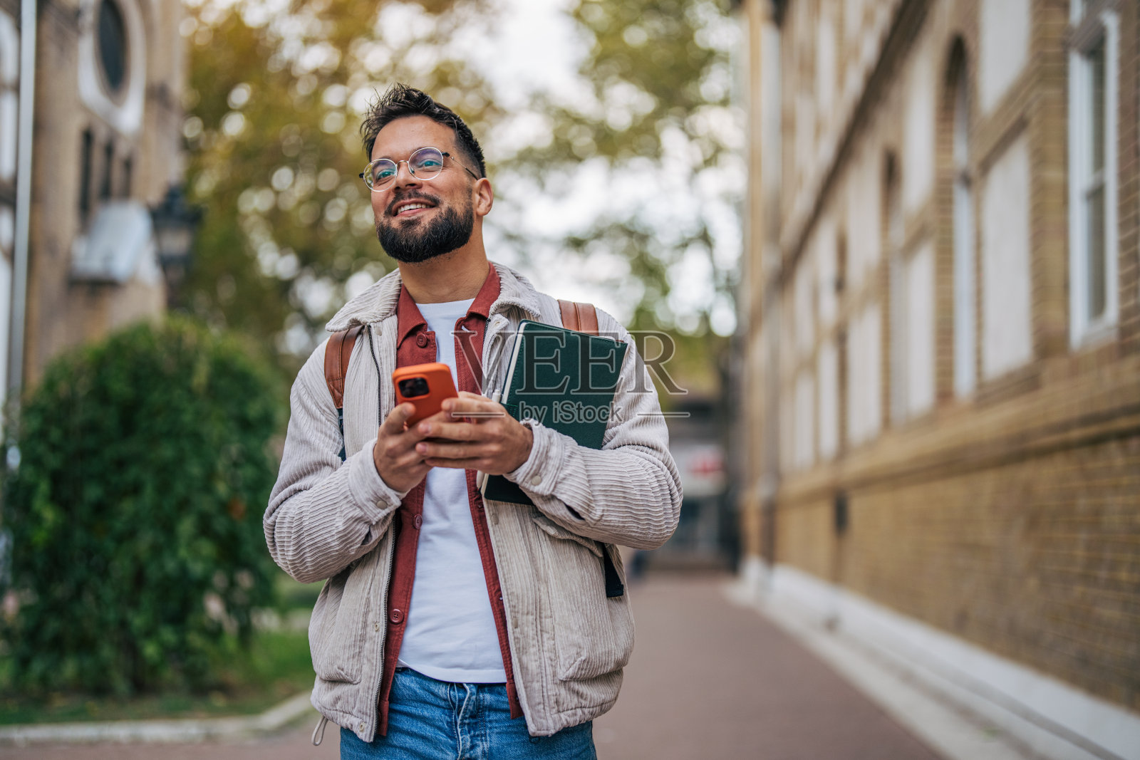 一名快乐的男学生站在大学外面。照片摄影图片