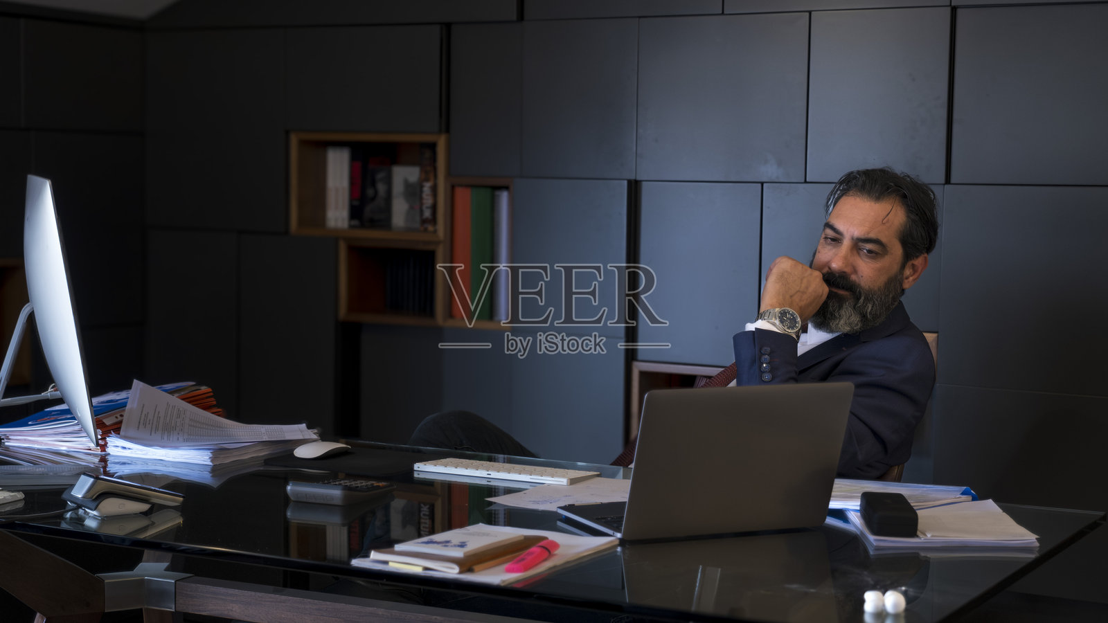 一位中年黑发商人在办公室的桌子上认真工作，专注于他的电脑。照片摄影图片