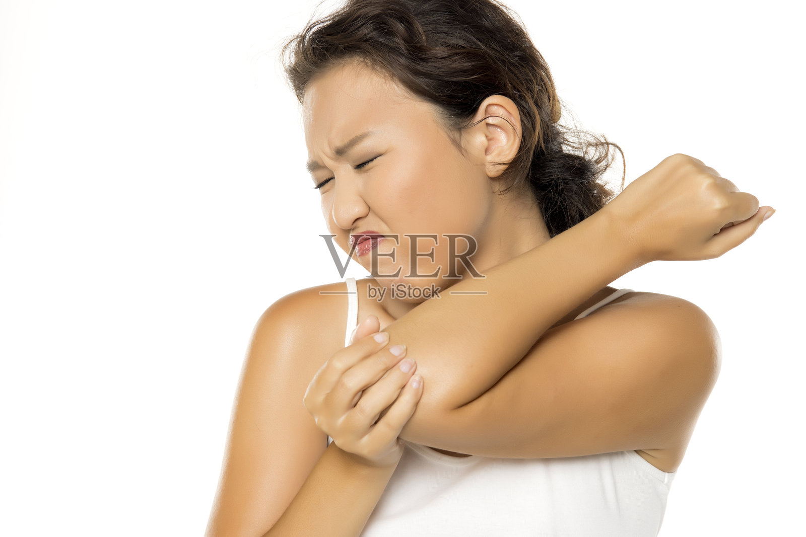 一位亚洲女性手肘疼痛，捂着手肘，脸上露出痛苦的表情。照片摄影图片
