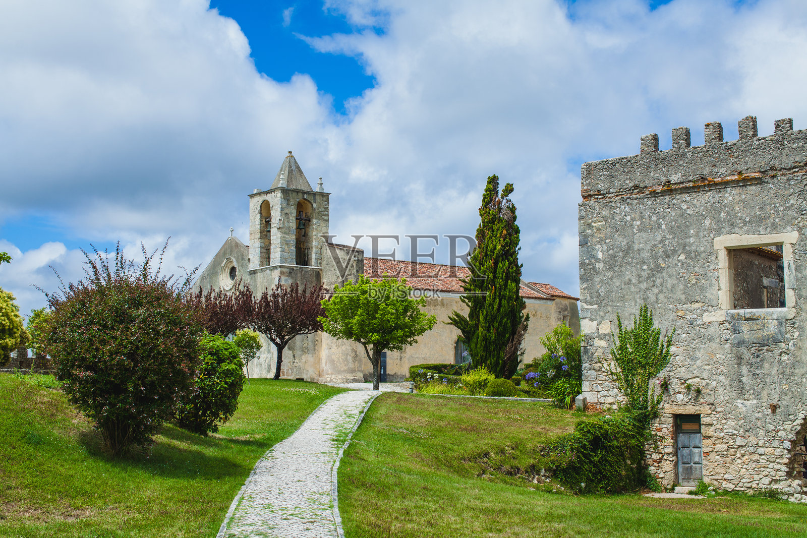 一条狭窄的石头小路穿过草地，通向一座历史建筑和遗址，天空部分多云。照片摄影图片