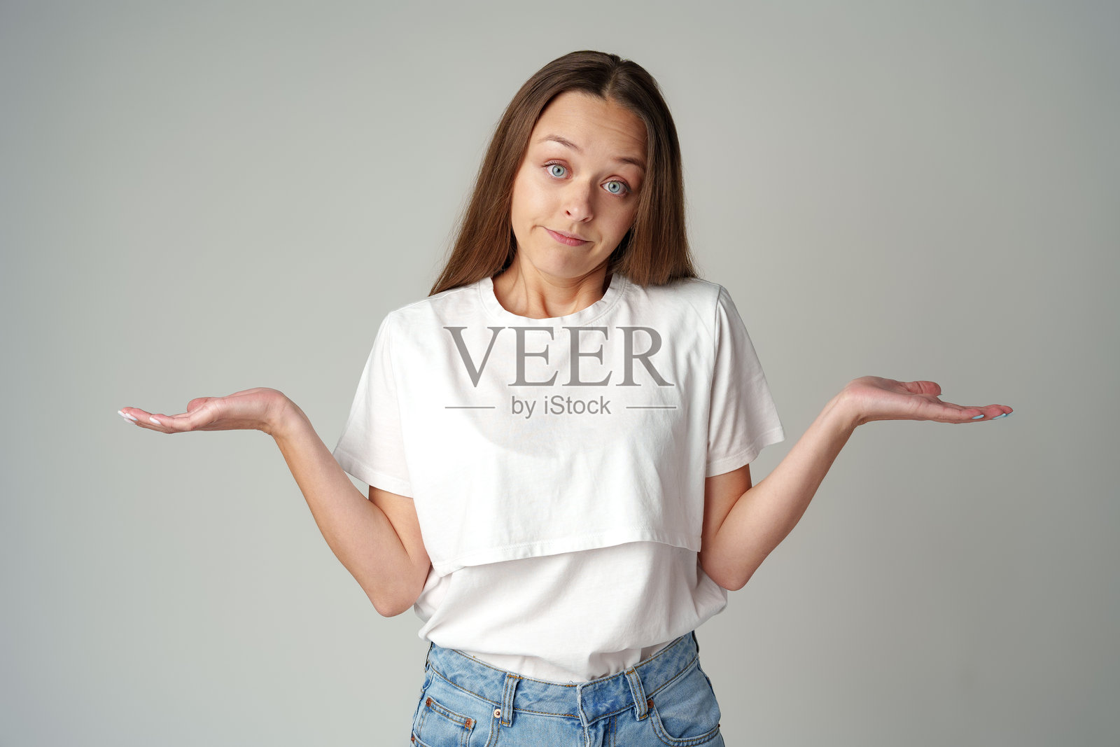 一位无助的年轻女性感到担忧，不知道该说什么，面前一片灰色背景。照片摄影图片