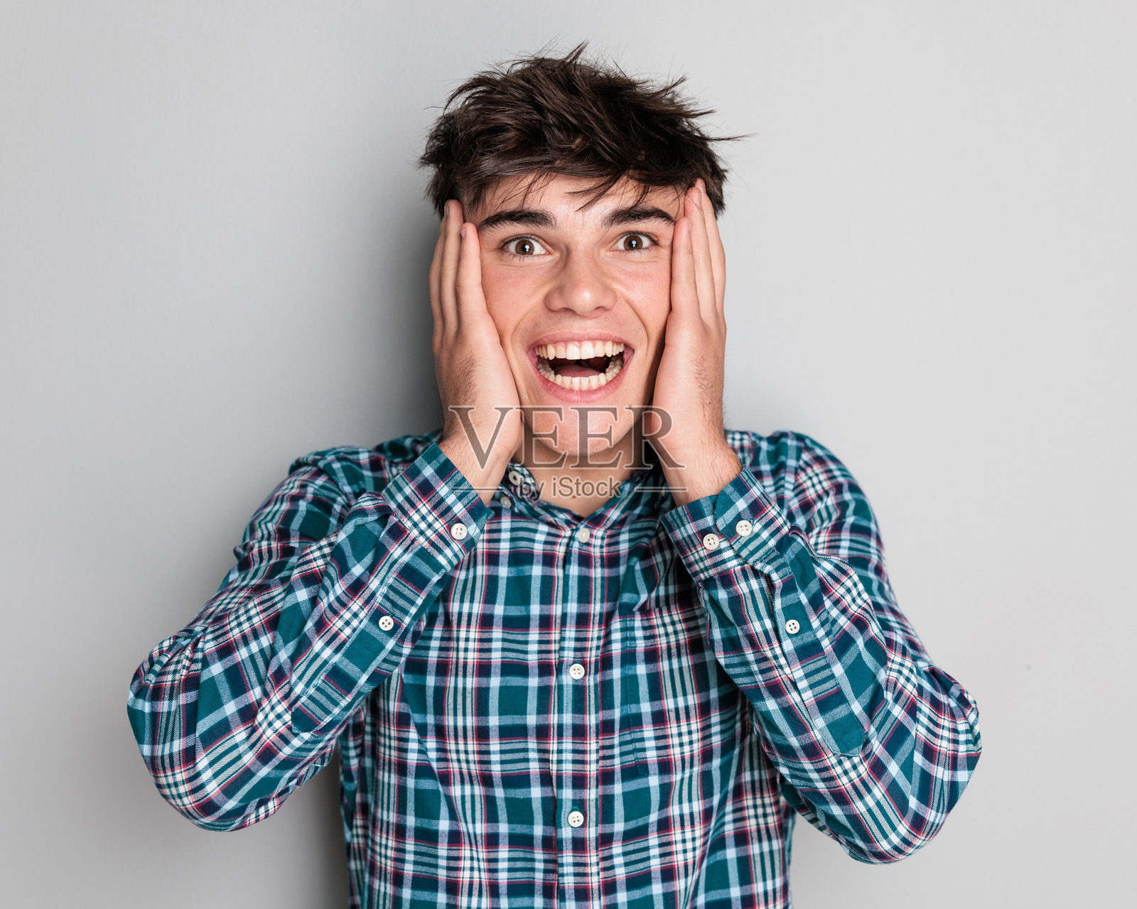 惊讶的年轻男子用手掌捂住太阳穴并大笑照片摄影图片