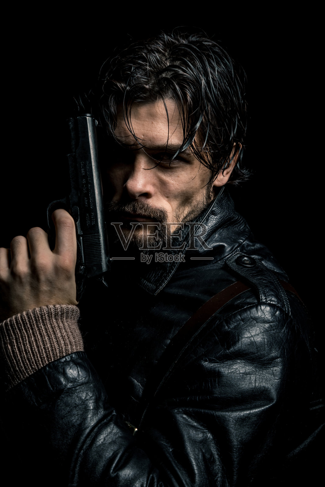 严肃男子手持枪支，站在黑色背景前照片摄影图片