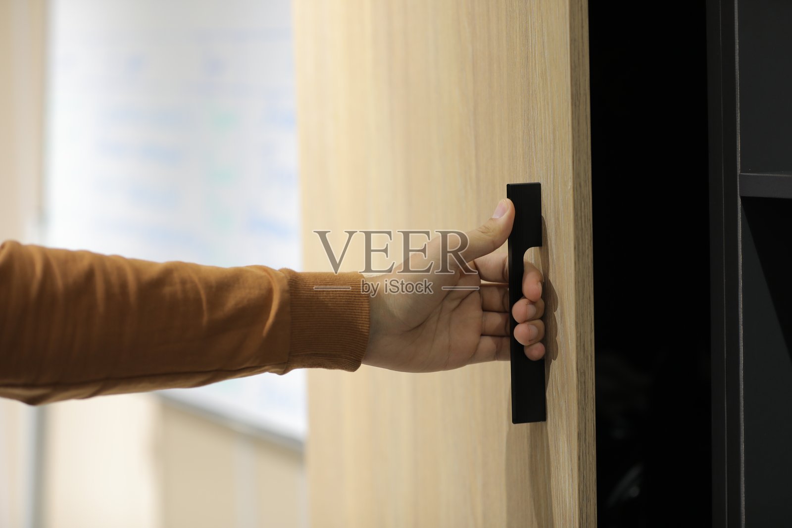 一个人正在打开一个带黑色把手的门。照片摄影图片