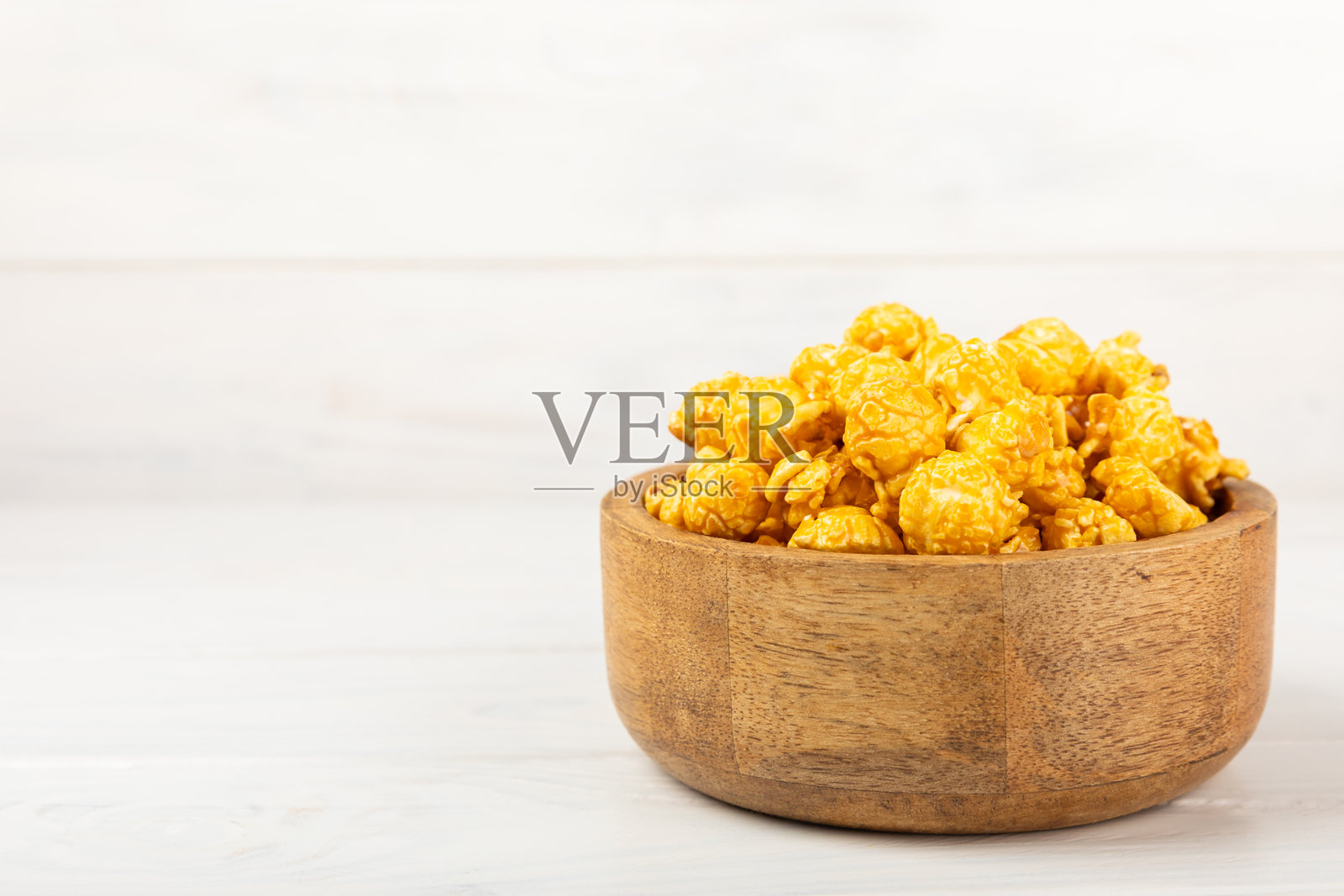 甜美的焦糖爆米花放在木质背景的碗中。咸焦糖爆米花。焦糖酱。特写。装饰。留白。照片摄影图片