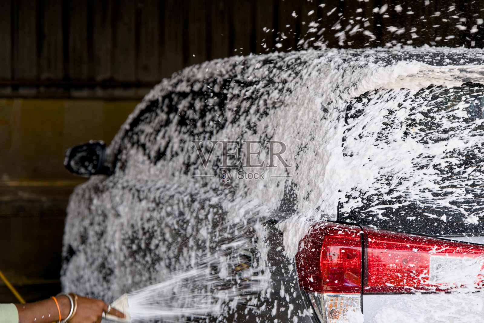 下午洗车场内，泡沫肥皂和水喷洒在车辆上的洗车活动照片摄影图片