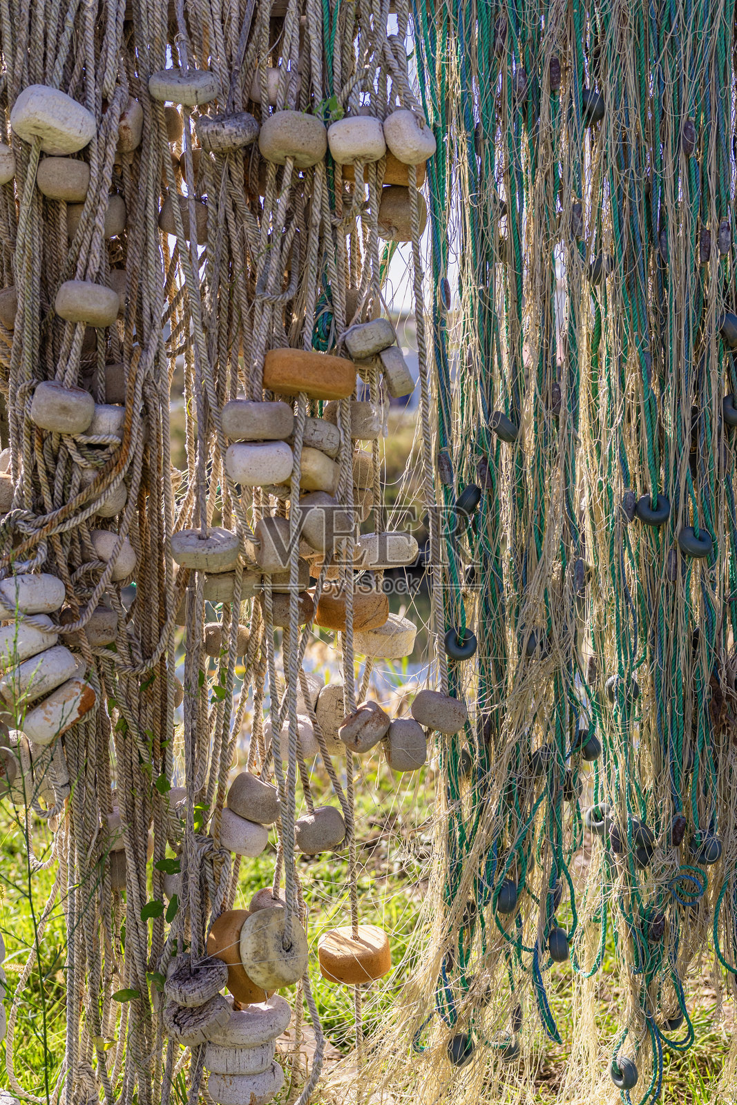 五彩斑斓的渔浮漂在海岸地区的破旧渔网旁悬挂。照片摄影图片