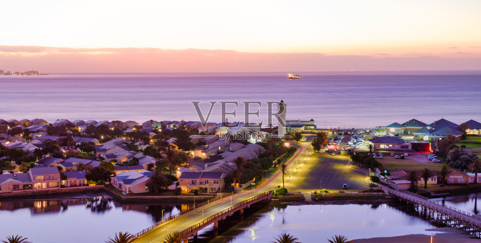 伍德布里奇岛，展示其标志性的灯塔和连接桥梁，街道和房屋的灯光营造出温暖的氛围照片摄影图片