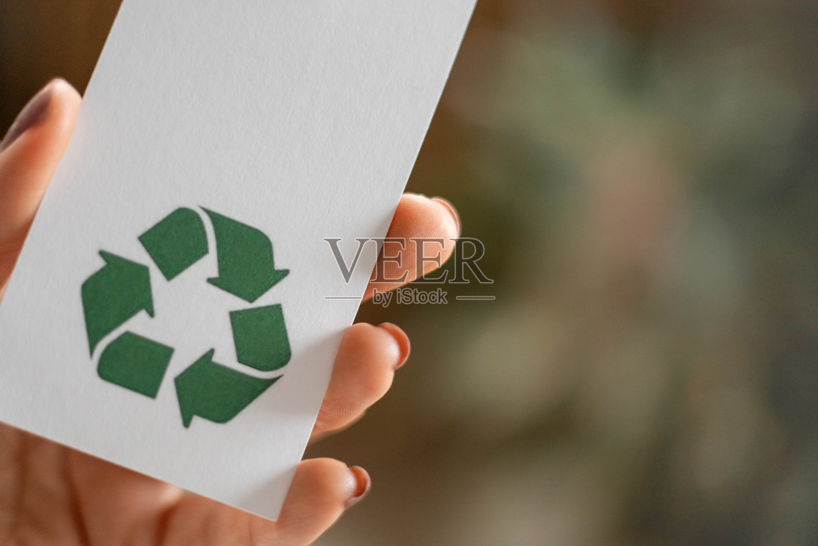 可回收产品概念。手拿着写有“100%回收材料”的标签。照片摄影图片