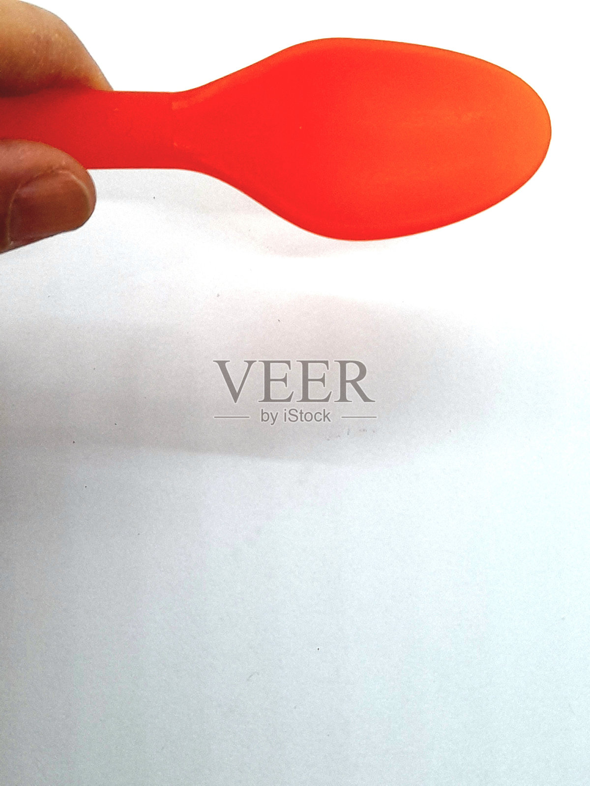 一把橙色塑料勺子，背景为白色照片摄影图片