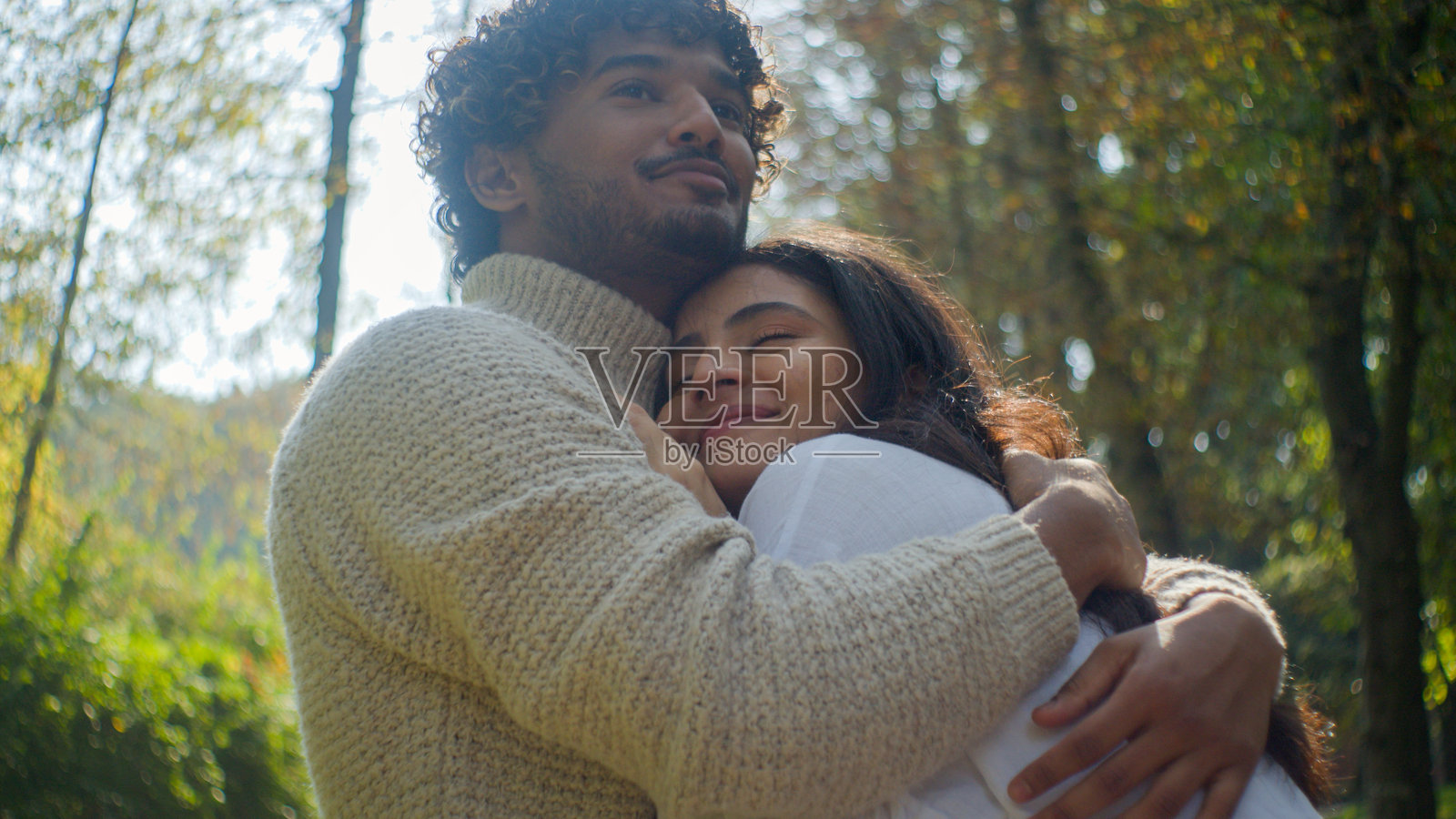 无忧无虑的阿拉伯印度情侣，男士拥抱女士，微笑着享受在公园的亲密时光，浪漫约会，男士与女士亲密接触，依偎在一起，度蜜月。照片摄影图片