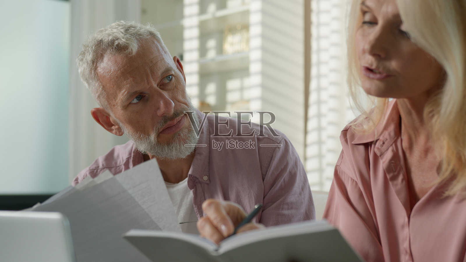 疲惫而沉思的白人夫妇，家庭中的祖父母，成熟的女性和退休的男性在家中的沙发上讨论业务，处理文件、账单和银行付款。照片摄影图片