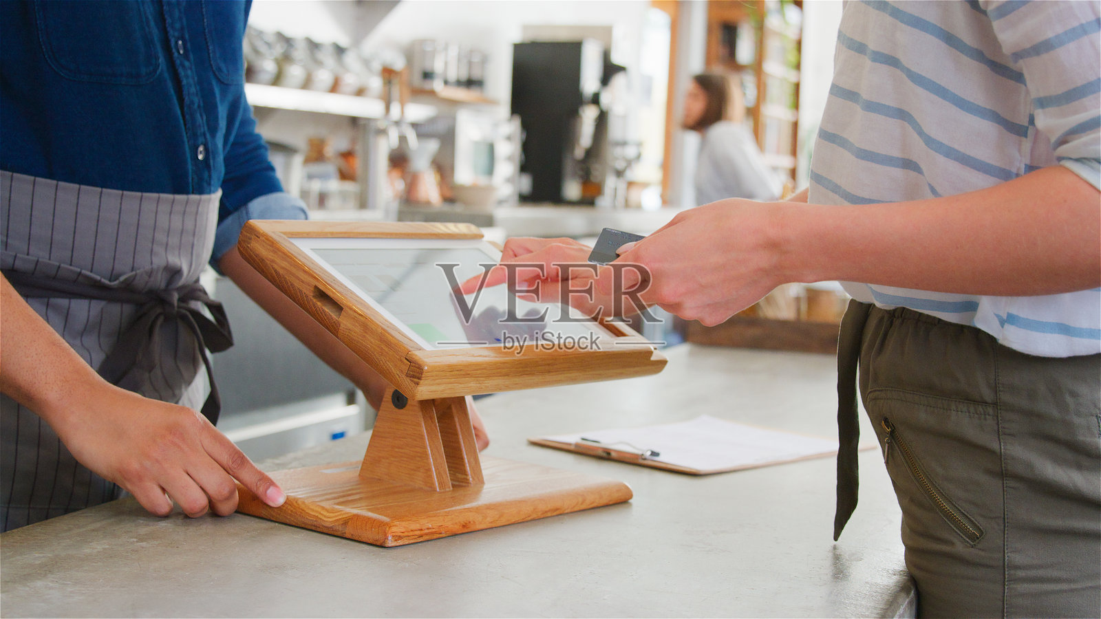 咖啡店中男性工作人员与女性顾客进行非接触式卡支付的特写镜头照片摄影图片