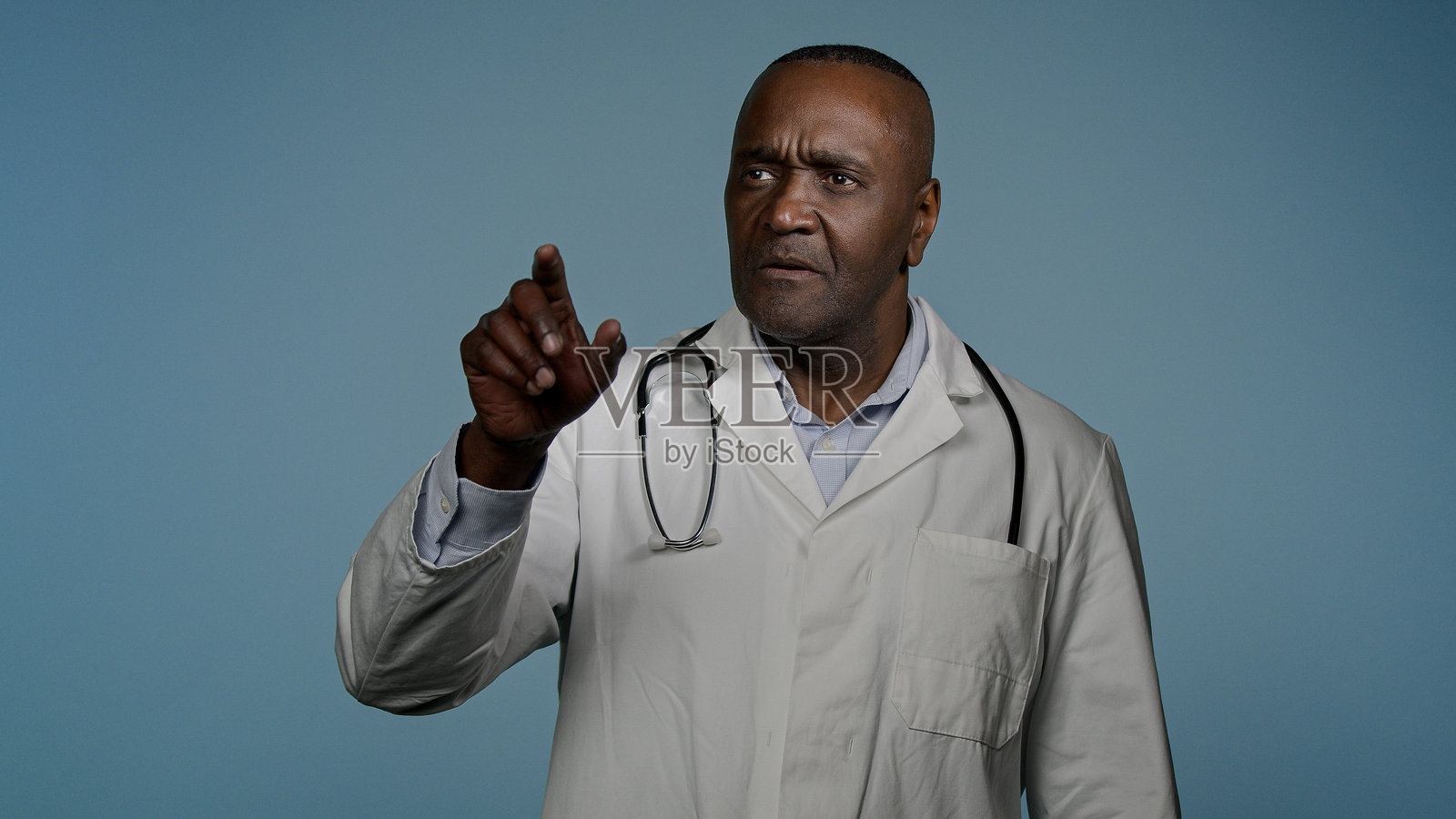 专注的非裔美国男性医生，专业的医疗工作者，在蓝色背景下用手在空中模拟使用现代创新技术进行3D全息诊断。照片摄影图片