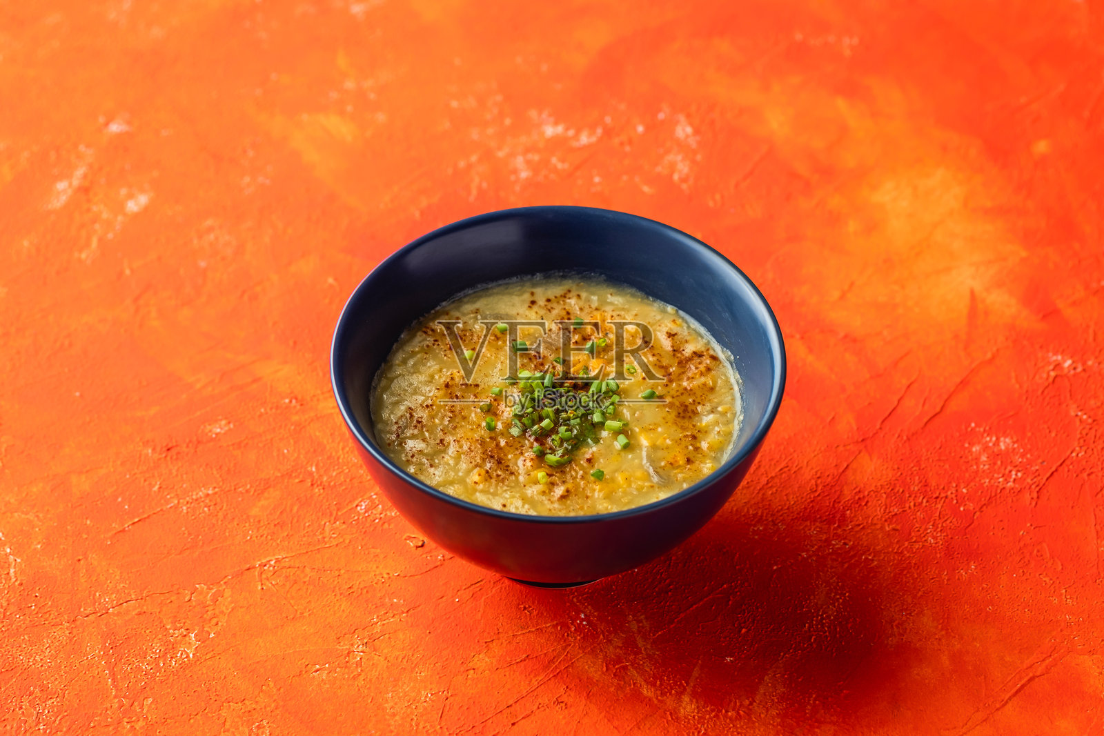 甜玉米浓汤配青葱，盛在碗中，背景为橙色，侧面视角的热饮。照片摄影图片