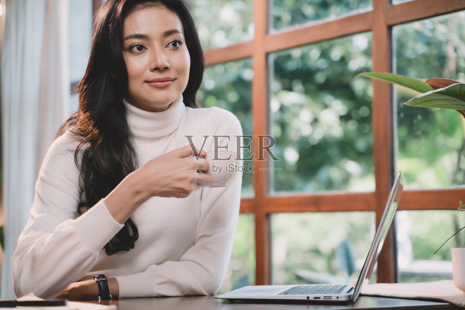 女商人在咖啡店里喝咖啡、使用智能手机，享受放松时光。年轻女性坐着，面带微笑，感到快乐。照片摄影图片