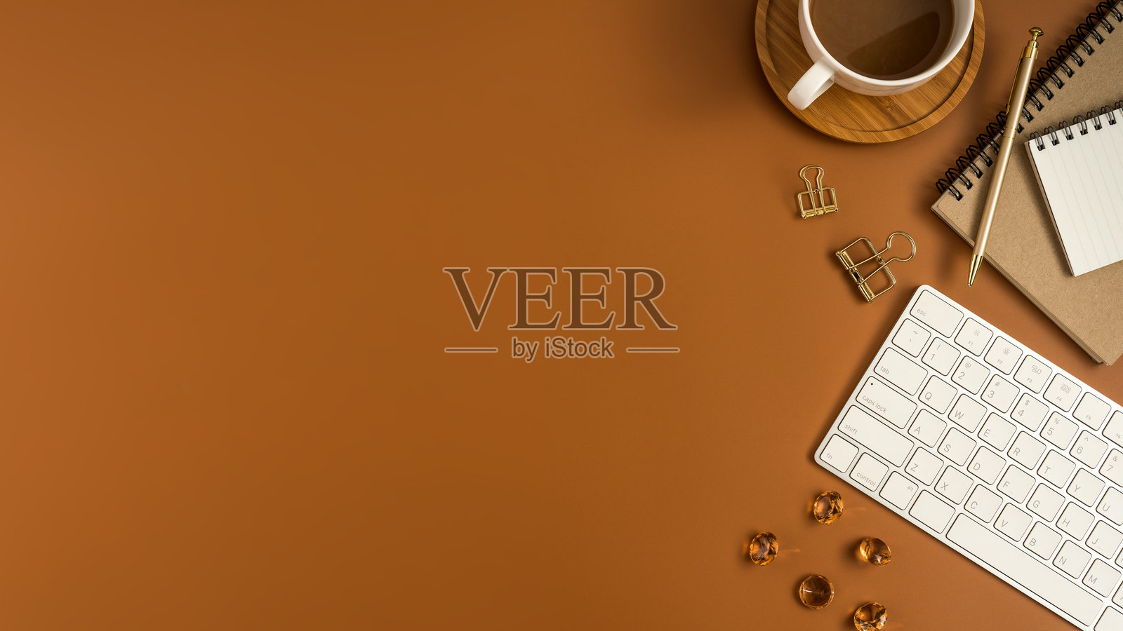 高角度视图的笔记本电脑，旁边有饮料和办公用品，背景为棕色照片摄影图片