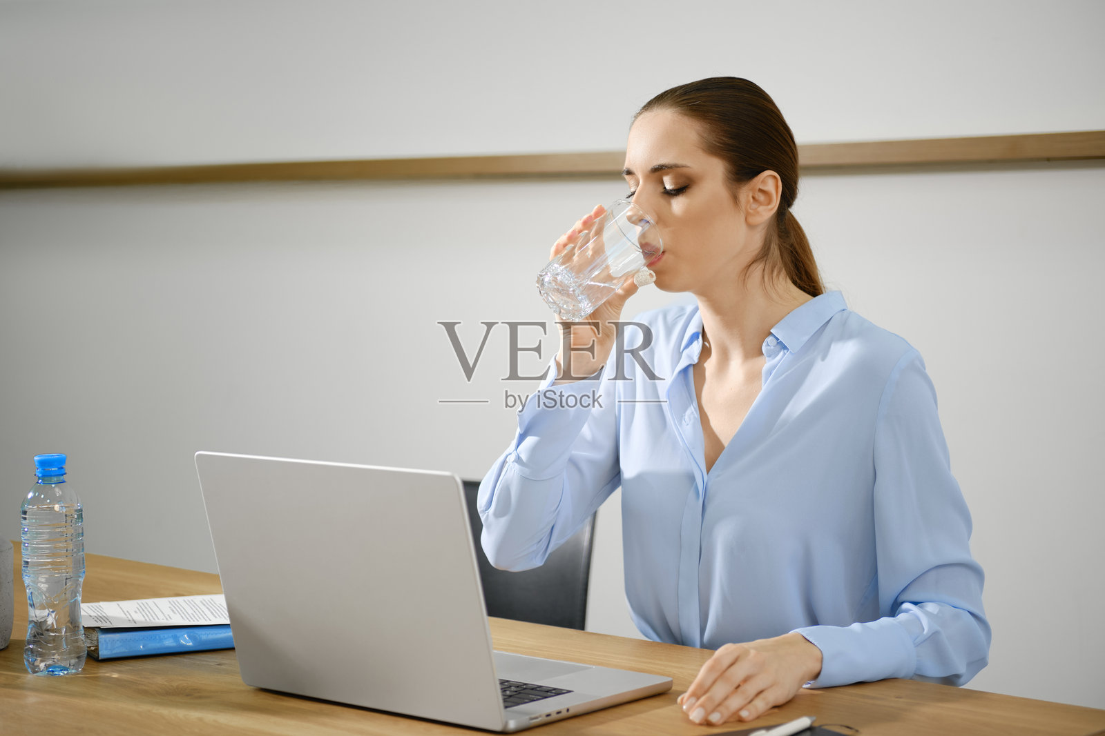 职业女性在明亮的办公室里工作时，休息喝水。照片摄影图片