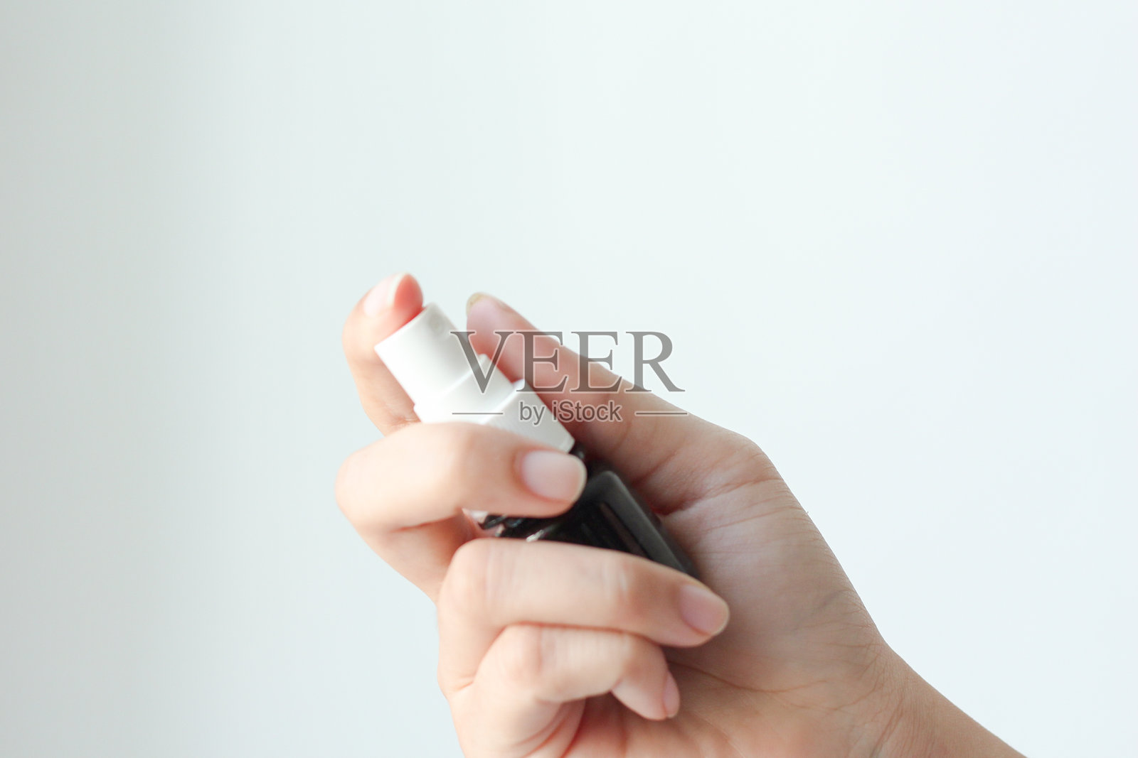 白色背景下，手持喷雾瓶的人特写照片摄影图片